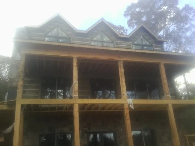 Dormers and porch framing on a large log home under construction — Roof Coating work by our crew in Fowler